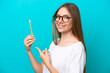 Young Lithuanian woman brushing teeth over isolated background and pointing it