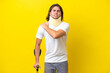 © luismolinero - Young handsome man wearing neck brace and crutches isolated on yellow background suffering from pain in shoulder for having made an effort