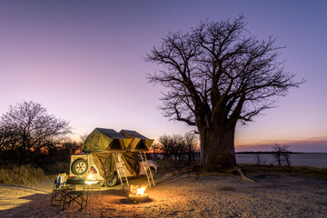 africa - camping in the wilderness with fire and sundowner in front of a baobab tree, nxai pan, bots