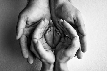 children's foot in the hands of mother, father, parents. feet of a tiny newborn close up. little bab