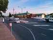 © Austockphoto - cars on road passing bus stop and train station in country town at dusk
