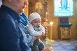 A small child at a baby christening ceremony in a church. the godfather holds a little boy in his arms. Baptism of a newborn. The sacrament of baptism. Child and God