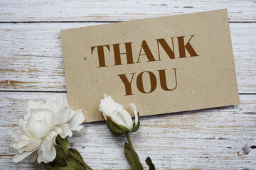 Sticker - Thank You text message on paper card with flower decoration on wooden background