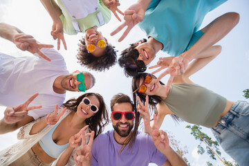 Wall Mural - Low angle view photo of cheerful carefree buddies show v-sign enjoy warm sunny weather journey outdoors