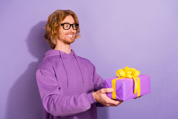 Poster - Photo of cool wavy orange hairstyle guy give gift wear eyewear purple sweatshirt isolated on pastel violet color background