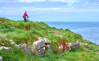 Wall Mural - nice senior woman on mountain bike, cycling on the cliffs of Cnoc an Daimh, Kilgalligan the northern part of the Republic of Ireland