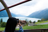 Fototapeta Tulipany - Young Asian tourist women using her smartphone to taking photo of natural scene while travel in Brienz Switzerland. Tourist attraction view point on the way to Rothorn Bahn with copy space.