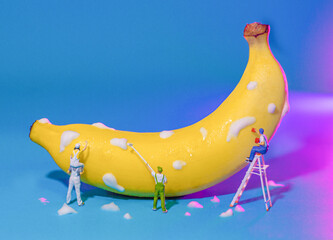 miniature people is cleaning the banana on blue background