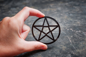 Wall Mural - Black pentagram in hand against dark background