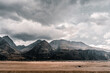 © FranciscoJavier - large field on the treeless plain near the lonely sad mountains under a threatening sky with many gray and black clouds on a stormy day, mount cook, new zealand