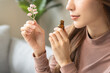 © KMPZZZ - Aromatherapy, asian young woman, girl hand holding flower, bottle of essential perfume oil, enjoying smell fragrance of herbal from medicine natural organic at home.Therapy treatment, beauty skin care