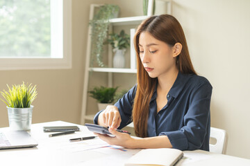 Wall Mural - Account finance, asian young business woman hand use calculator for calculate budget, cost and income of company from charts, reports paperwork, plan spend money expenses, working on desk at home.