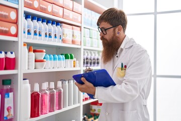 Canvas Print - Young redhead man pharmacist writing on document at pharmacy