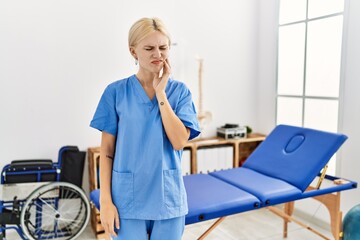 Poster - Beautiful caucasian physiotherapist woman working at pain recovery clinic touching mouth with hand with painful expression because of toothache or dental illness on teeth. dentist