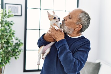 Sticker - Senior grey-haired man smiling confident kissing chihuahua at home