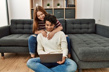 Poster - Young couple smiling happy using laptop sitting on the sofa at home.