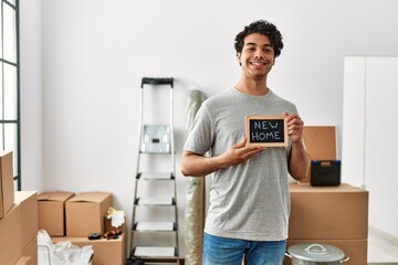 Canvas Print - Young hispanic man smiling happy holding blackboard with new home message.