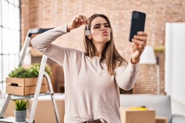 Poster - Beautiful woman holding keys of new home showing on video call looking at the camera blowing a kiss being lovely and sexy. love expression.