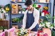 Young hispanic man florist make bouquet of flowers at florist shop