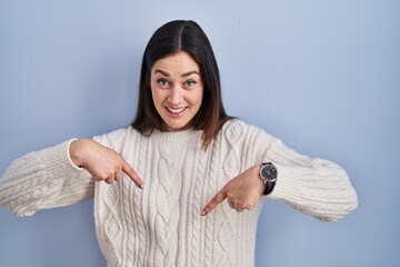 Poster - Young brunette woman standing over blue background looking confident with smile on face, pointing oneself with fingers proud and happy.