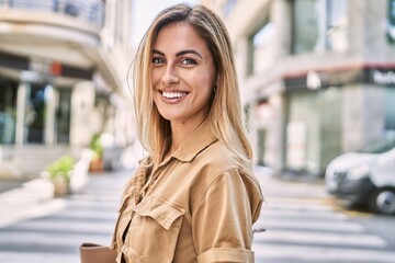 Young blonde girl smiling happy standing at the city.