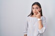 Young hispanic woman standing over white background pointing to the eye watching you gesture, suspicious expression