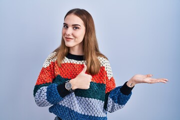 Wall Mural - Young hispanic girl standing over blue background showing palm hand and doing ok gesture with thumbs up, smiling happy and cheerful