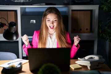 Canvas Print - Young caucasian woman working at the office at night celebrating surprised and amazed for success with arms raised and open eyes. winner concept.