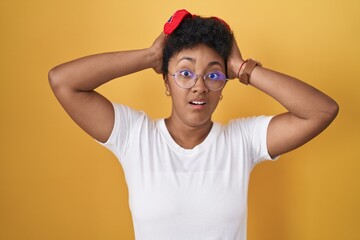 Sticker - Young african american woman standing over yellow background crazy and scared with hands on head, afraid and surprised of shock with open mouth