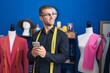 © Krakenimages.com - Young caucasian man tailor smiling confident using smartphone at clothing factory