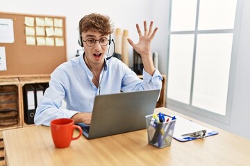 Canvas Print - Young caucasian man wearing call center agent headset at the office celebrating victory with happy smile and winner expression with raised hands