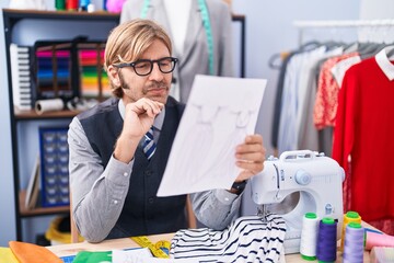 Poster - Young blond man tailor looking clothing design draw at clothing factory