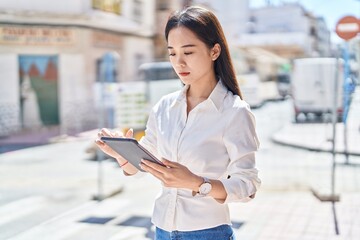 Sticker - Young chinese woman using touchpad with serious expression at street