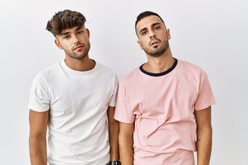 Wall Mural - Young gay couple standing over isolated background looking sleepy and tired, exhausted for fatigue and hangover, lazy eyes in the morning.