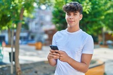 Young Hispanic Teenager Smiling Confident Using Smartphone At Park