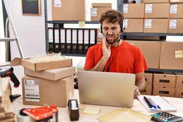 Poster - Young hispanic call center agent man working at warehouse touching mouth with hand with painful expression because of toothache or dental illness on teeth. dentist concept.