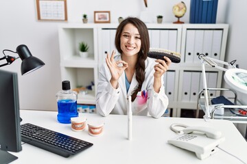 Poster - Young dentist woman comparing teeth whitening doing ok sign with fingers, smiling friendly gesturing excellent symbol