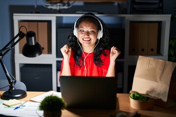 Wall Mural - Young asian woman working at the office with laptop at night celebrating crazy and amazed for success with arms raised and open eyes screaming excited. winner concept