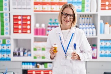 Sticker - Young blonde woman pharmacist smiling confident holding pills bottles at pharmacy