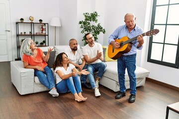 Sticker - Group of middle age friends having party playing classical guitar sitting on the sofa at home.