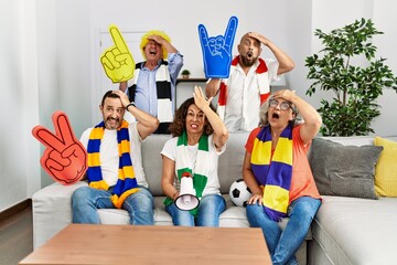 Wall Mural - Group of senior people supporting soccer team at home stressed and frustrated with hand on head, surprised and angry face