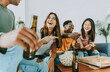 © Davide Angelini - Group of friends watching tv and eating pizza - Multiracial cheerful young people having weekend home party together - Happy students having fun in university rooms - Youth lifestyle and food concept