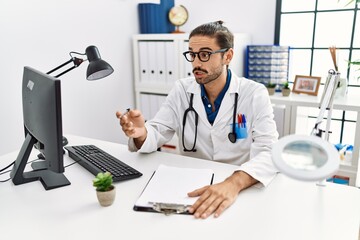 Wall Mural - Handsome hispanic man working as doctor speaking to a patient at hospital clinic