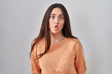 Canvas Print - Young brunette woman standing over white background making fish face with lips, crazy and comical gesture. funny expression.