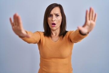 Sticker - Middle age brunette woman standing wearing orange sweater doing stop gesture with hands palms, angry and frustration expression