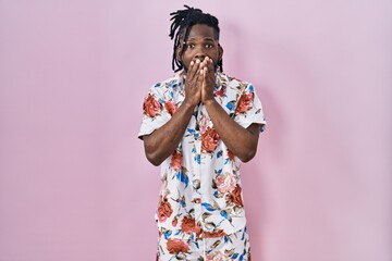 Sticker - African man with dreadlocks wearing summer shirt over pink background shocked covering mouth with hands for mistake. secret concept.