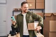 © Krakenimages.com - Young caucasian man ecommerce business worker using smartphone holding package at office