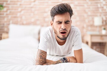 Poster - Young hispanic man lying on bed yawning at bedroom