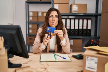 Sticker - Young brunette woman working at small business ecommerce cutting credit card making fish face with mouth and squinting eyes, crazy and comical.