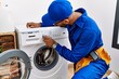 © Krakenimages.com - Young arab man wearing technician uniform repairing washing machine at laundry room